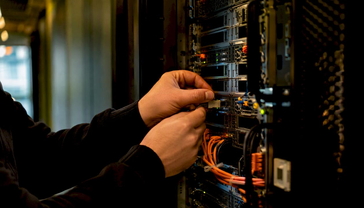 Hands connecting network cable to server