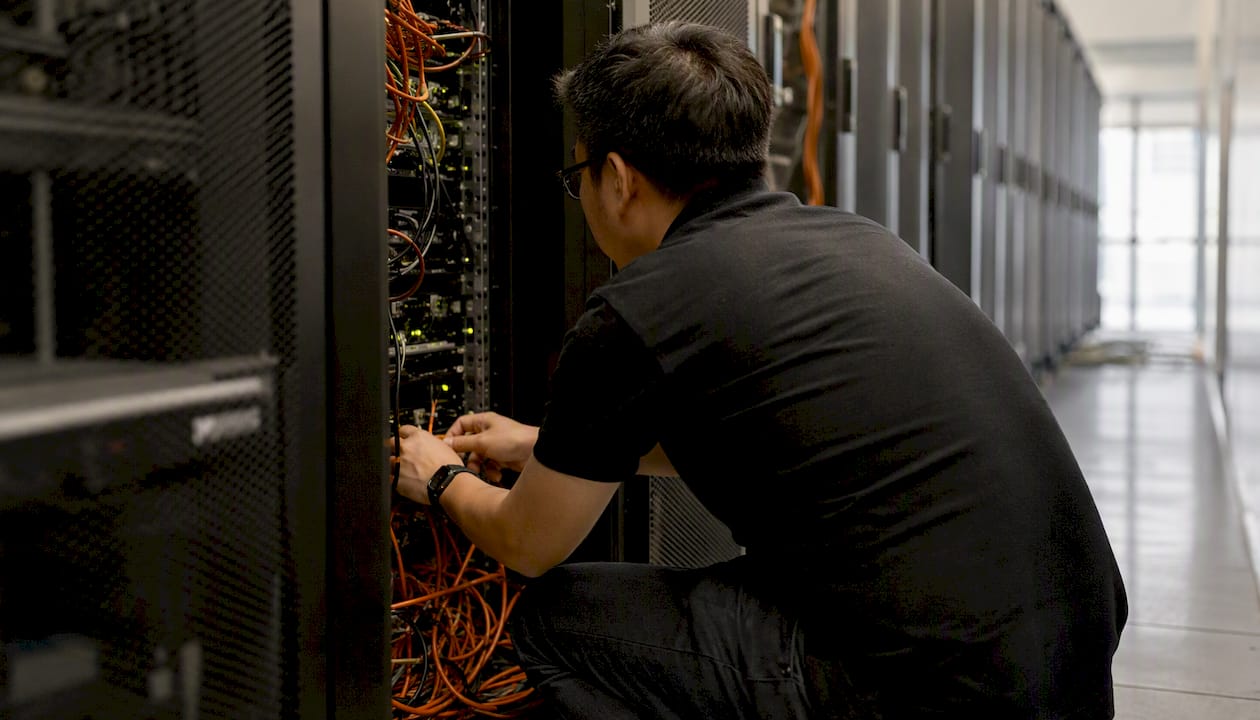 Hands plugging power cable into server rack