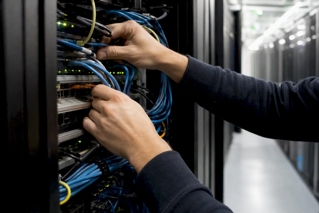 Hands configuring cables inside server rack